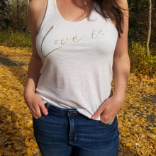 Load image into Gallery viewer, A model in a forest is wearing a oatmeal coloured tank top with the words Love is in gold font